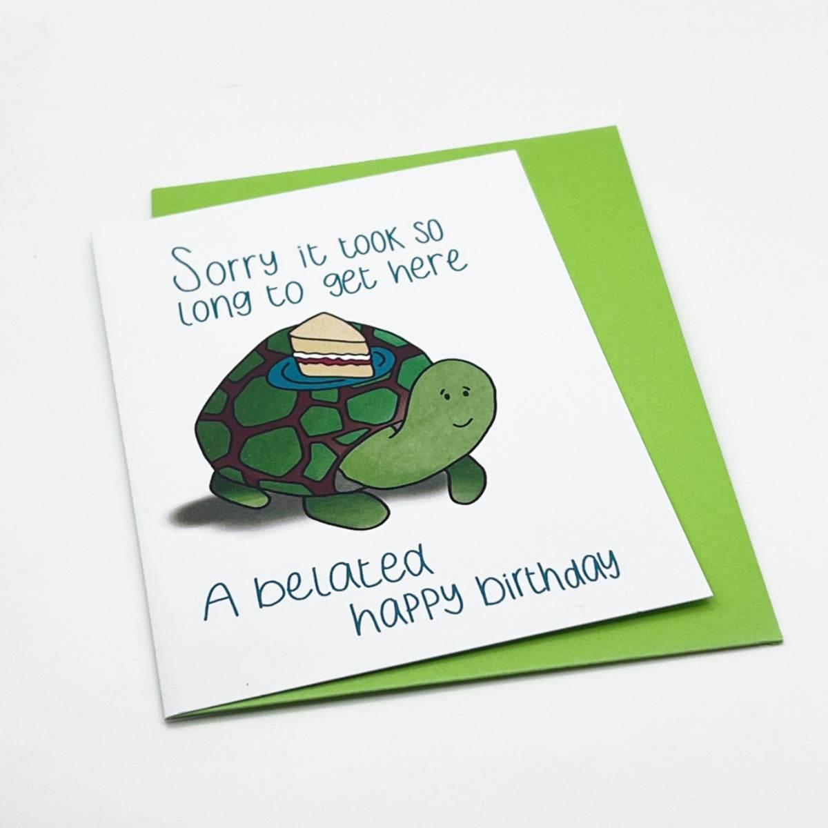 Introducing our Belated Birthday Card: This charming card showcases a delightful illustration of a green turtle carrying a slice of cake on its shell. The thoughtful message reads, "Sorry it took so long to get here. A belated happy birthday." Made from biodegradable materials, the card comes with a vibrant green envelope.