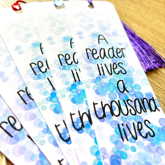 A close-up of the vibrant "A Reader Lives a Thousand Lives" bookmark, perfect for any book enthusiast, beautifully laid out on a wooden surface.