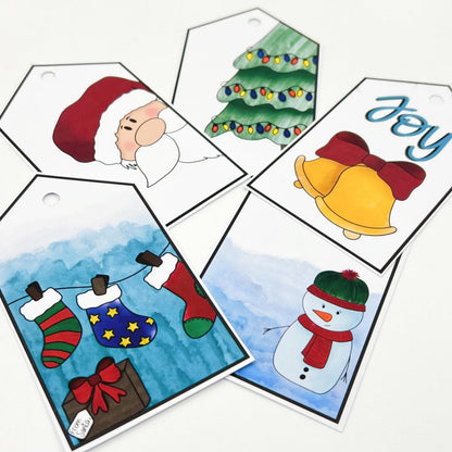 Five festive holiday gift tags featuring a Santa, decorated tree, bells, stockings, and snowman arranged on a white surface are perfect for festive wrapping. Each tag adds a touch of handmade charm to your gifts, with the Christmas Tree Gift Tag standing out beautifully.