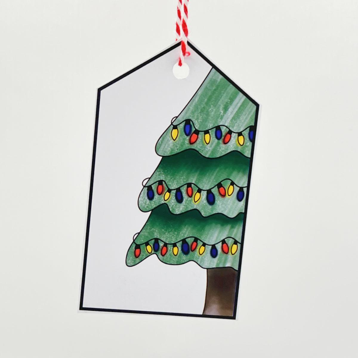 The Christmas Tree Gift Tag is a handmade tag featuring a hand-drawn Christmas tree adorned with colorful lights, framed in black, and attached to a red and white string.