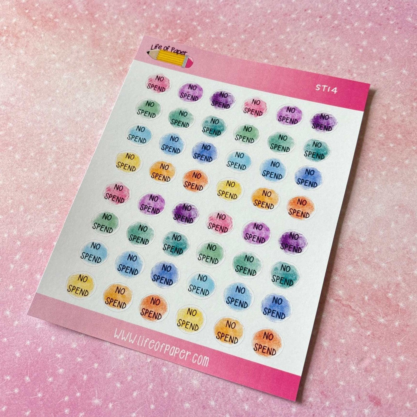 A sheet of vibrant round stickers, each emblazoned with the phrase "NO SPEND," is displayed against a pink, speckled background. These No Spend Planner Stickers are available in a variety of colors such as blue, green, purple, and yellow—ideal for your savings challenge or budget planning needs.