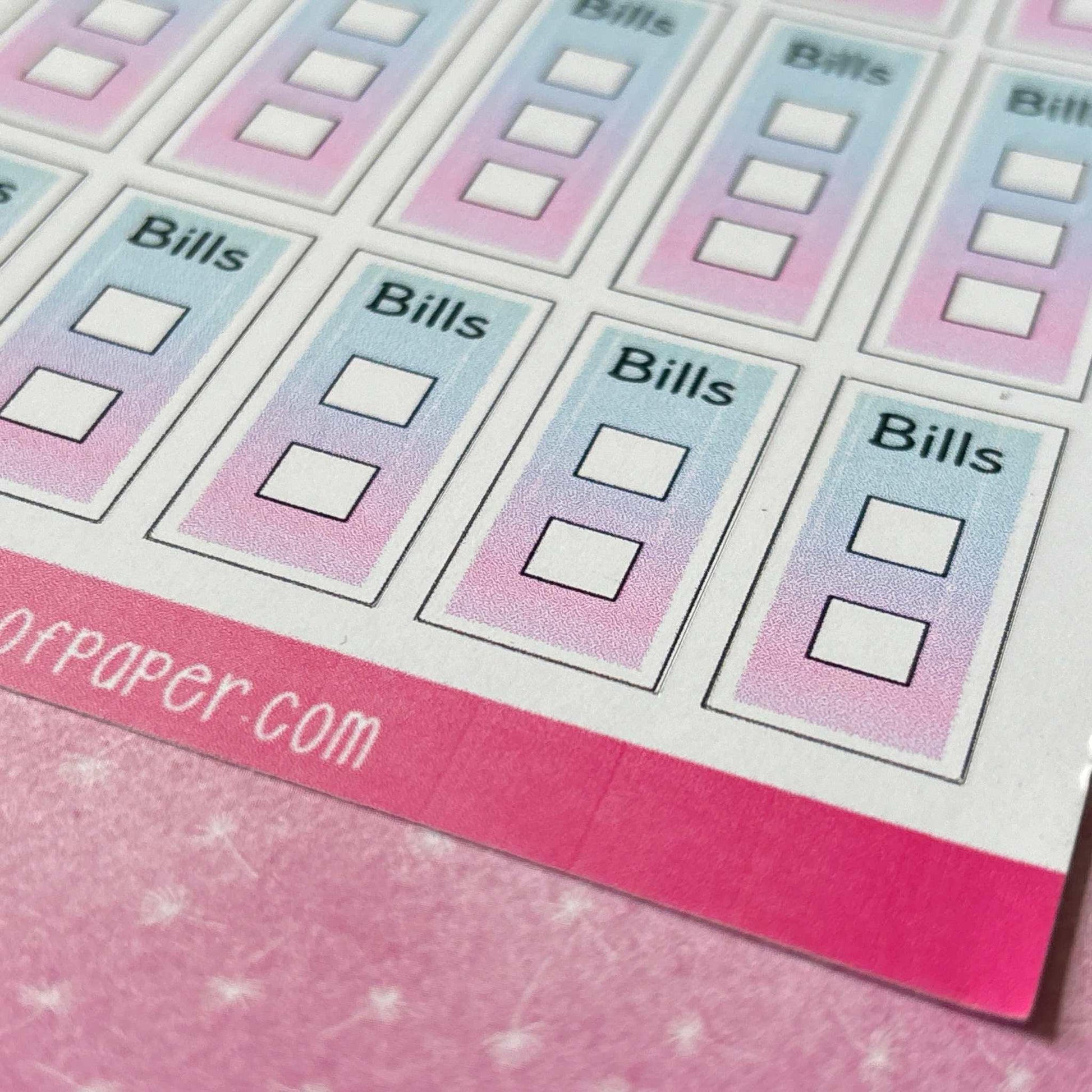 A sheet of rectangular "Bill Tickbox Planner Stickers" with gradient colors and checkboxes, perfect for your bill tracker pages, placed on a pink surface.