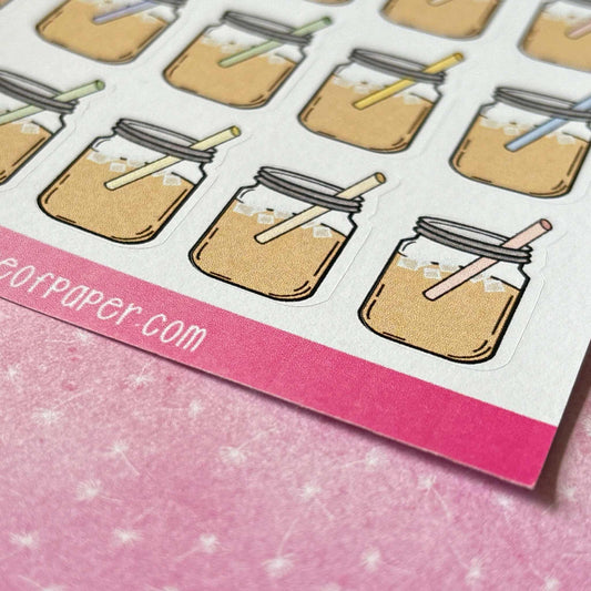 Stickers of iced coffee in mason jars with straws placed on a pink surface. "dearpaper.com" is partially visible at the bottom-left corner. Perfect for adding a touch of summer drink vibes to your collection, these Mason Jar Stickers are a delightful addition!