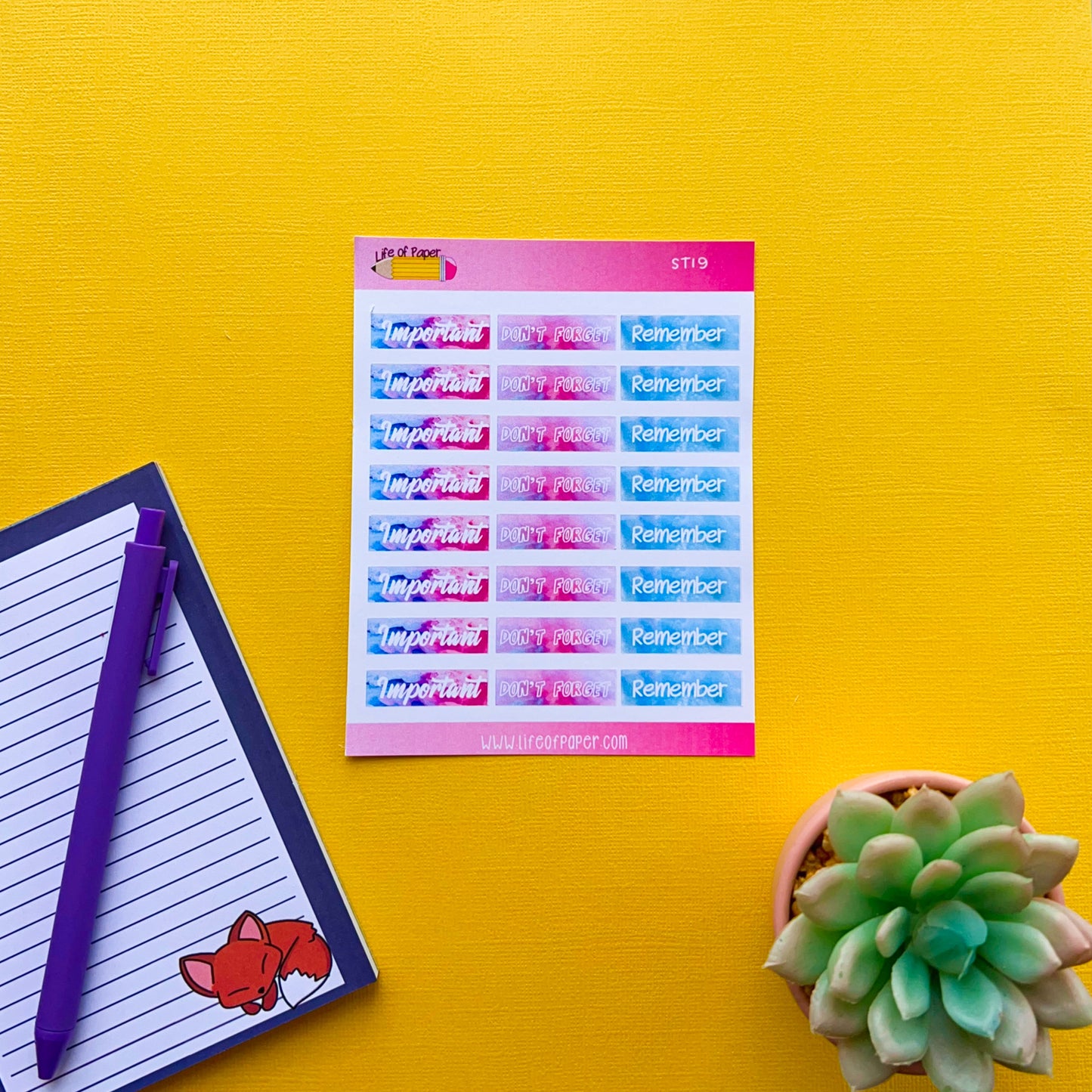 A colorful set of Bright Heading Planner Stickers on a sheet rests on a vibrant yellow surface. Next to it is a lined notepad with a purple pen and a cute fox illustration. A small green succulent in a pot is also part of the scene, perfect for helping you organise your planner with stylish reminder headings.