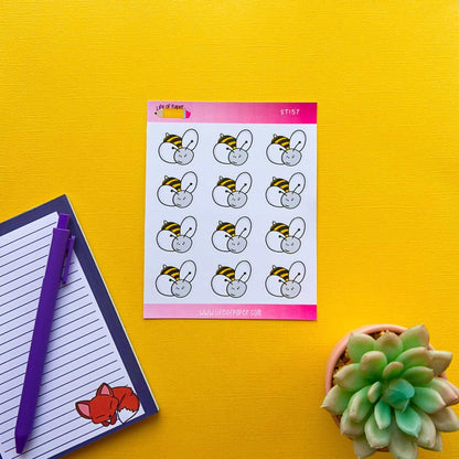 A top-down view of a yellow surface with a notepad and purple pen on the left, a succulent plant on the right, and the Bumblebee Sticker Sheet in the center. The stickers feature cute bumblebee faces and a white mouse wearing a bee outfit. The notepad's cover has a small sticker of a fox.