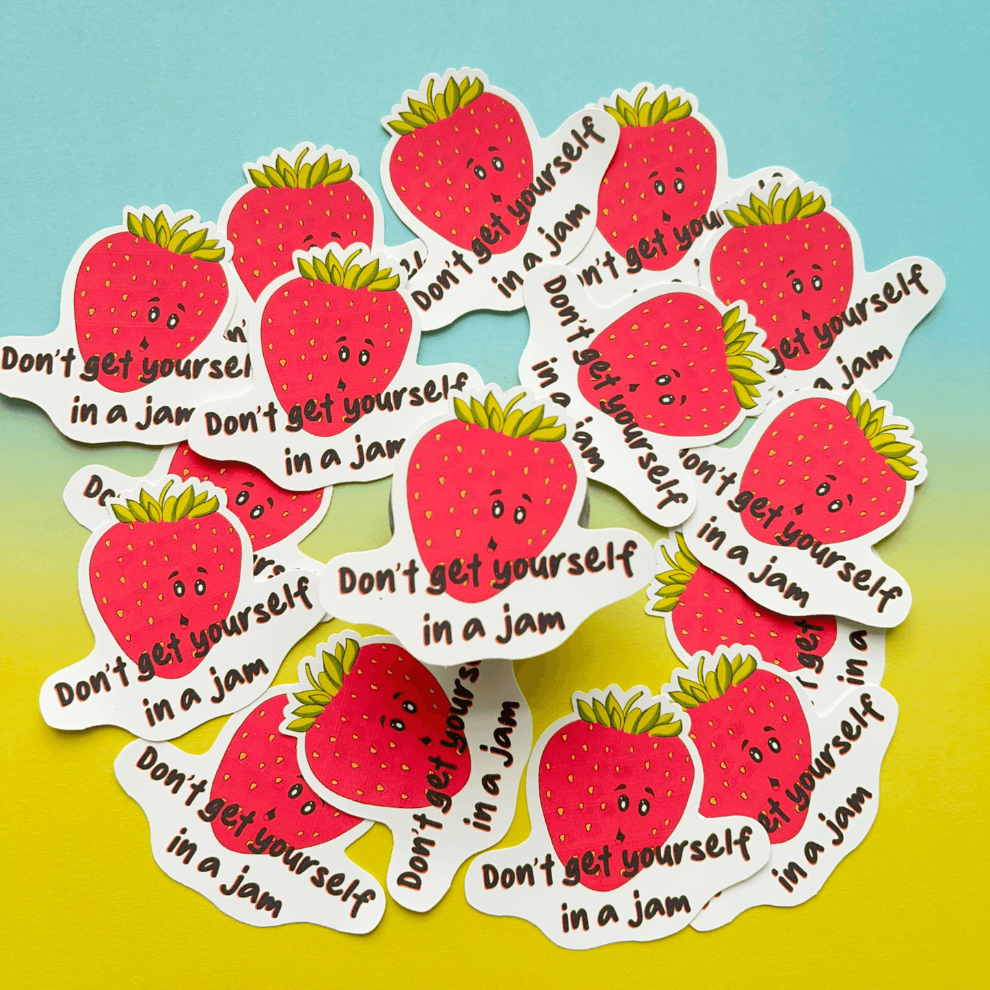 The Strawberry Sticker, featuring an assortment of strawberry-shaped vinyl stickers with the text "Don't get yourself in a jam," showcases a delightful blue and yellow gradient background. These stickers not only bring a playful pun to your collection but are also water resistant.