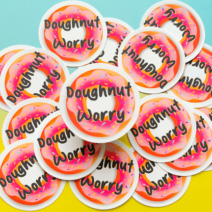 A collection of durable matte Doughnut Stickers, showcasing an image of a pink frosted doughnut accompanied by the phrase "Doughnut Worry." These water-resistant stickers are ideal for adding a sweet touch to any surface.