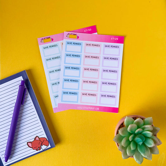 Two sheets of stickers labeled "SAVING AMOUNT PLANNER STICKERS" are placed on a bright yellow surface. A lined notepad with a cartoon fox, accompanied by a purple pen, sits to the left. A small succulent plant is on the bottom right corner of the image. Perfect for your Save Money Planner or Happy Planner enthusiasts!