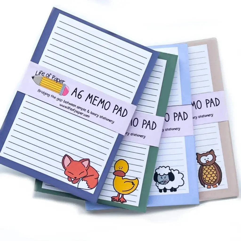 Four colorful Animal Collection Memo Pads are stacked, each featuring a cute animal illustration at the bottom right corner. The covers display a fox, duck, sheep, and owl. A band around this delightful gift set reads "A6 Memo Pad" and "Life of Paper." The lined sheets make these animal memo pads both charming and practical.