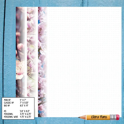 A notepad with a floral design on the left margin rests on a blue wooden surface. At the bottom left corner, a small chart lists various paper sizes. A pencil labeled "Elora Plans" lies at the notepad's bottom right, perfect for planning your day with Blossom Themed Notepaper.