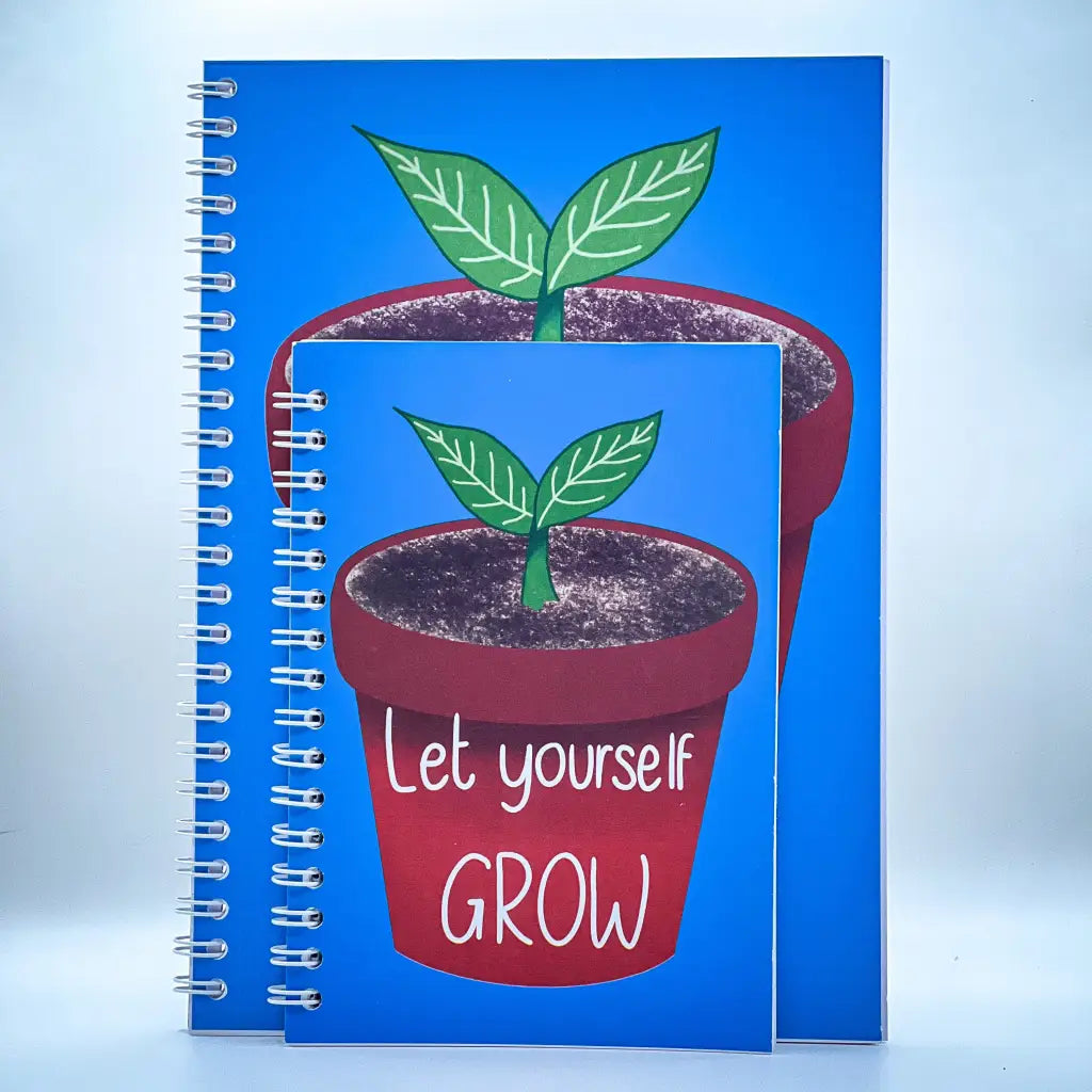 Two spiral-bound notebooks with blue covers, each featuring an illustration of a small potted plant with green leaves. The larger Let Yourself Grow Notebook has the phrase "Let yourself GROW" written below the pot, offering a self-esteem boosting message with its positive quote.