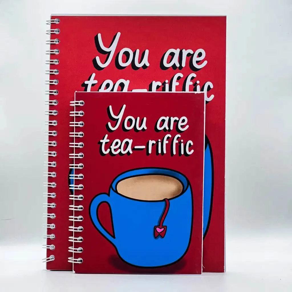 Two A6 plain notebooks with red covers feature the text "You are tea-riffic" and a blue cup of tea graphic. One notebook, ideal for note-taking, is larger than the other and each has 40 pages.