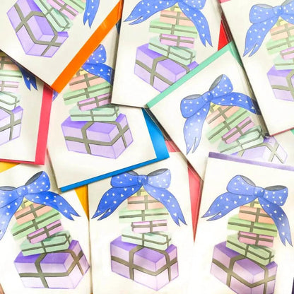 A stack of Pastel Birthday Cards features illustrations of birthday gifts tied with blue ribbons on a white background, scattered in a random arrangement.

