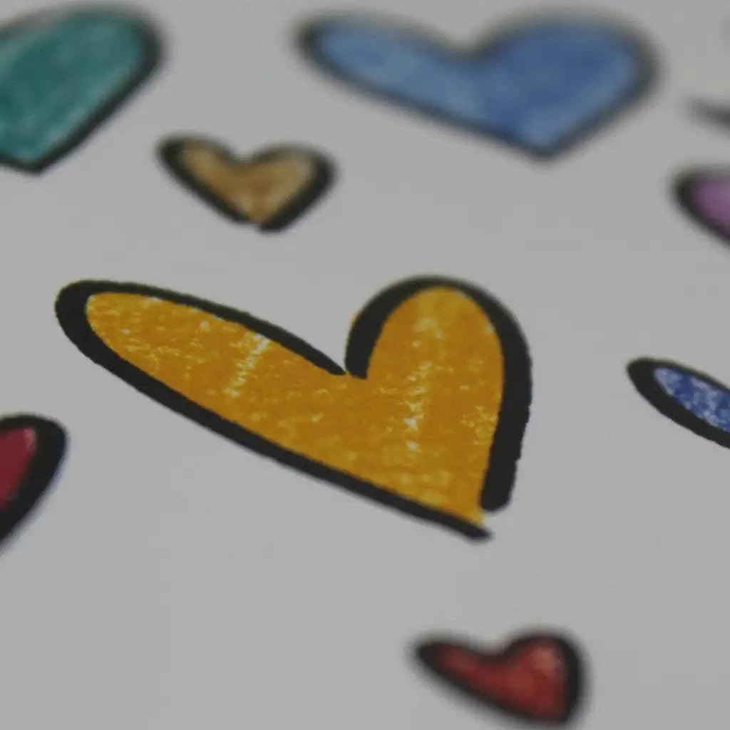 Close-up of various hand-drawn hearts, with one large yellow heart in the foreground surrounded by smaller hearts in different colors, creating a perfect design for the Rainbow Hearts Greeting Card.