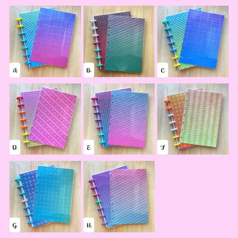 Eight Tiny Notes Notebooks with vibrant, geometric-patterned covers are arranged in two rows against a pink background. Each MAMBI Happy Planner compatible notebook has color-coded tabs labeled A through H. The covers feature gradient designs in shades of blue, pink, and green.